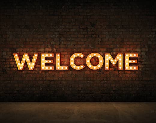 CAPS Community, welcome; lighted welcome sign on a brick wall