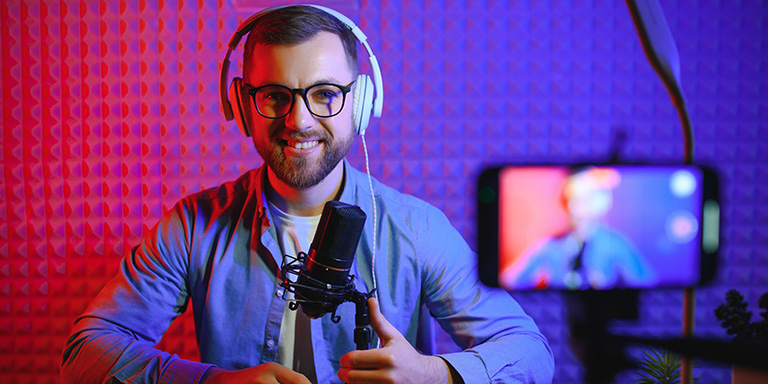 Man wearing headphones talking in a microphone while recording about podcasting for speakers