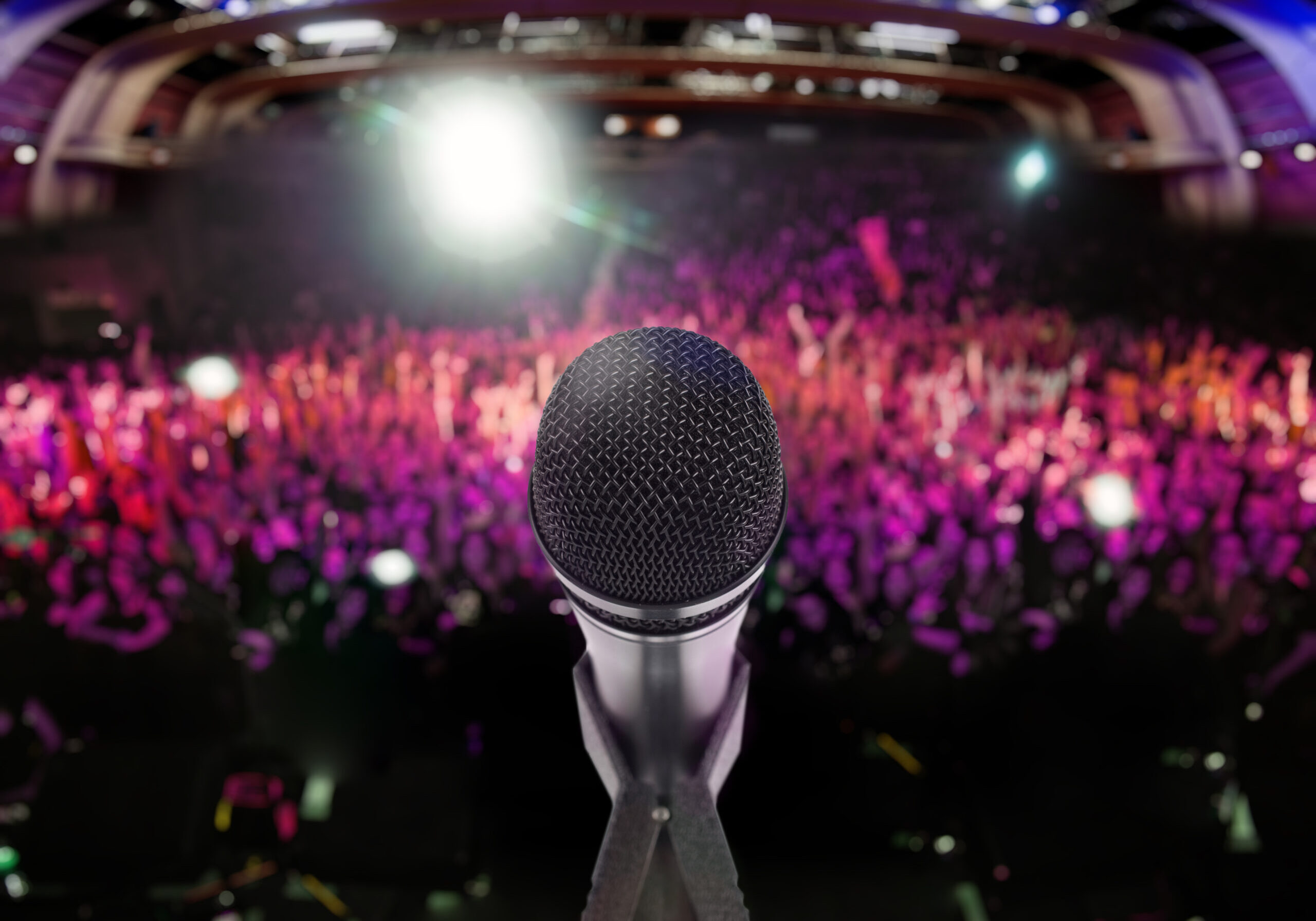 Microphone on stage with an audience on the background